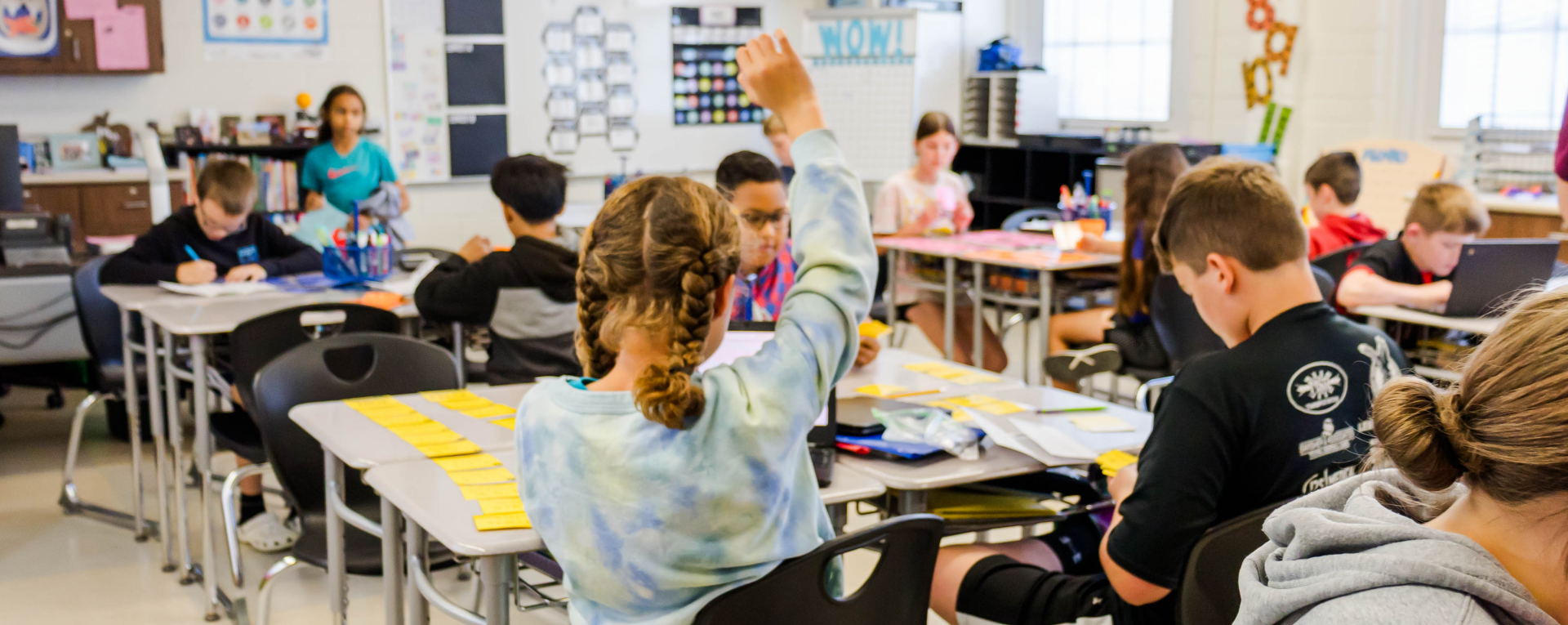 a group of students in a classroom with one student raising their hand